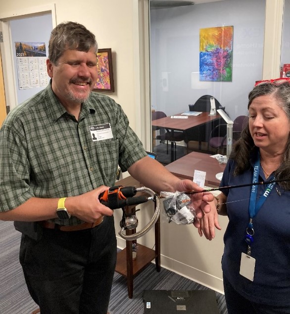 A man tries out an adaptive fishing pole that’s designed for one-handed use.