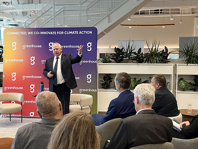 Governor Walz stands facing the camera, speaking to a crowd in front of him.