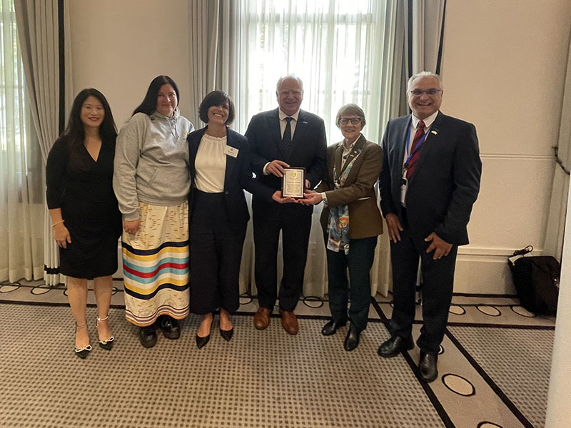 Governor Walz stands for a picture with a group of people holding a plaque.