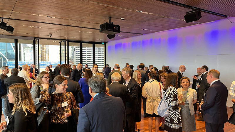 A large group of people stand around talking during a reception.