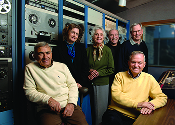 seated and standing people in radio broadcasting booth